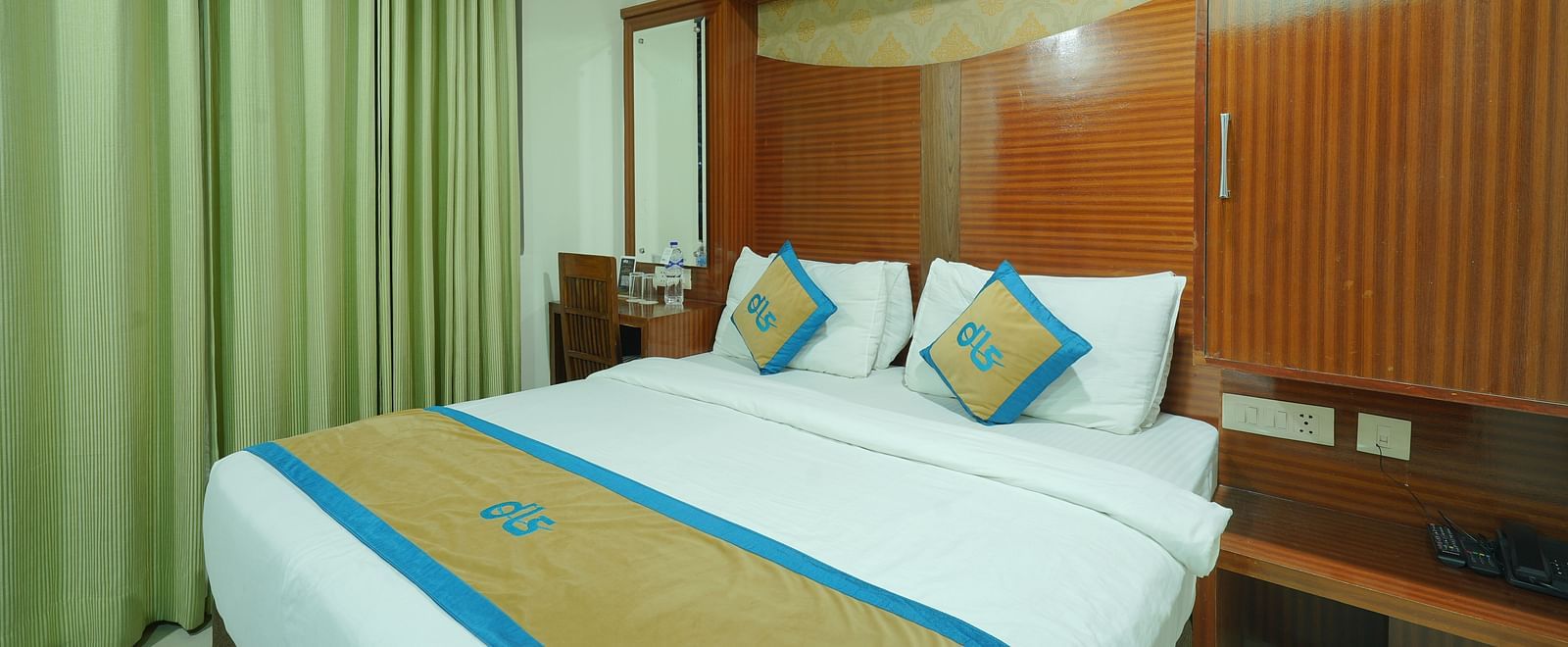 Deluxe room featuring a wooden headboard, a dressing table, a chair, and a mirror next to the bed at DLS Hotels The Rock Castle.